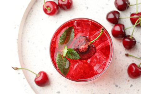 Tasty cherry soda with ice cubes, mint and berries on white table, flat layの写真素材