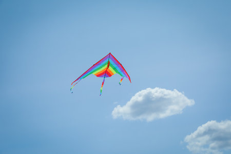 Colorful kite flying in blue sky, low angle viewの写真素材