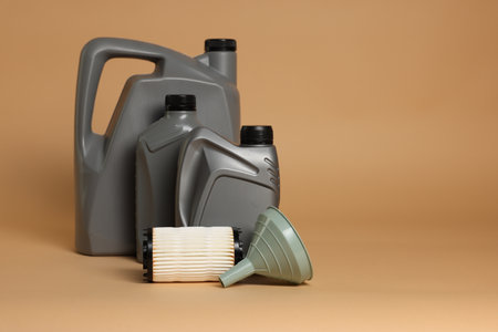 Motor oil in plastic canisters, filter and funnel on beige background, space for textの写真素材
