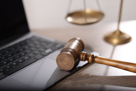 Judge. Laptop, gavel and scales on wooden table in office, closeupの写真素材