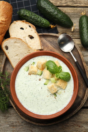 Tasty cucumber soup with croutons and basil served on wooden table, flat layの写真素材