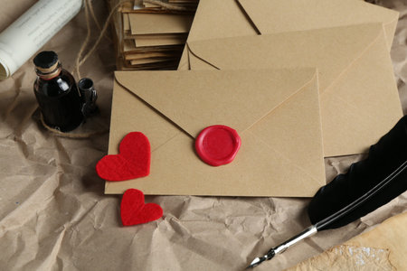 Stack of love letters, paper hearts, quill and ink on table, closeup