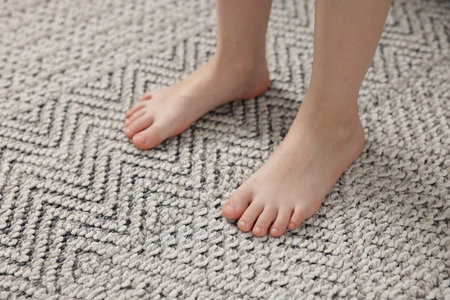 Girl on grey carpet at home, closeupの写真素材