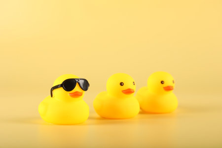 Three cute rubber ducks on yellow background, closeupの写真素材