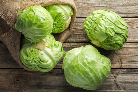 Fresh whole cabbages on wooden table, flat layの写真素材
