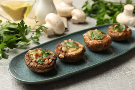 Delicious stuffed mushrooms with melted cheese and parsley on gray textured table, closeupの写真素材