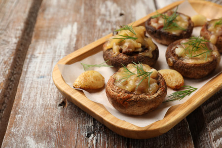 Delicious stuffed mushrooms with melted cheese, garlic and dill on color wooden table, closeupの写真素材