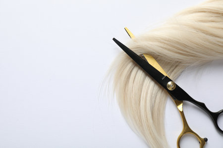 Hair lock and scissors on white background, top view. Space for textの写真素材