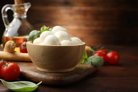 Tasty mozzarella cheese balls, breadsticks, tomatoes and basil on wooden table, closeupの写真素材