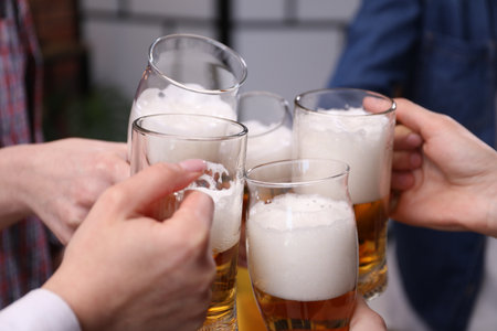 Friends clinking glasses of beer indoors, closeupの写真素材