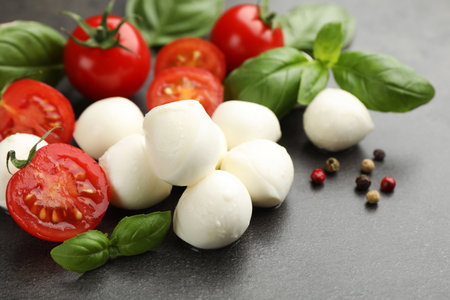 Mozzarella cheese, tomatoes, basil and peppercorns on gray table, closeupの写真素材