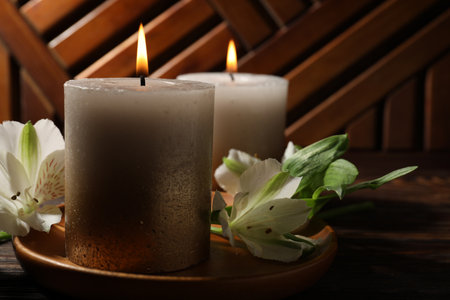 Burning candles and lily flowers on wooden table, closeupの写真素材