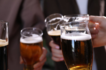 Friends clinking glasses of beer indoors, closeupの写真素材
