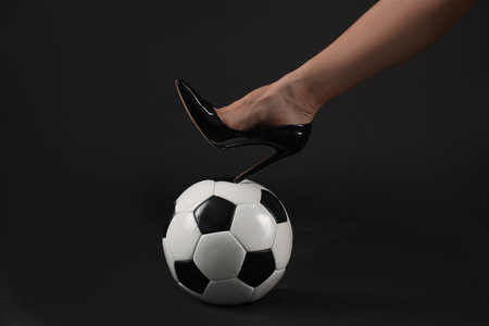 Woman in high heeled shoe with soccer ball on dark background, closeupの写真素材