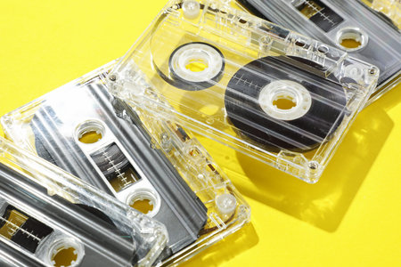 Audio cassettes with magnetic tapes on yellow background, closeup