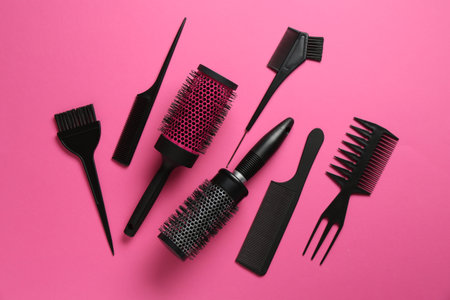 Different hairdresser's tools on pink background, flat lay