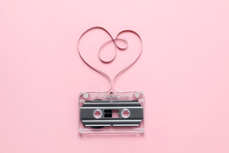 One audio cassette with heart shaped magnetic tape on pink background, top viewの写真素材