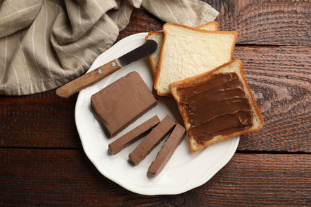 Sandwiches with chocolate butter and knife on wooden table, top viewの写真素材