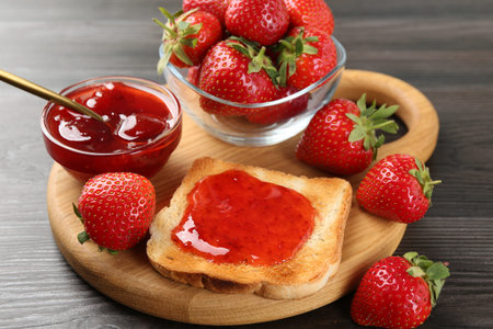 Toast with tasty homemade strawberry jam and berries on wooden table, closeup