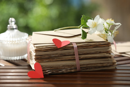 Stack of love letters, paper hearts and flowers on wooden table, closeupの写真素材