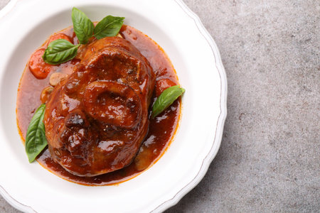 Traditional ossobuco dish with beef steak and sauce on grey table, top view. Space for textの写真素材