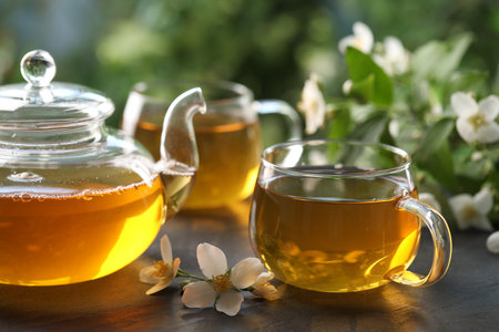 Tasty jasmine tea in cups, teapot and flowers on black table, closeupの写真素材