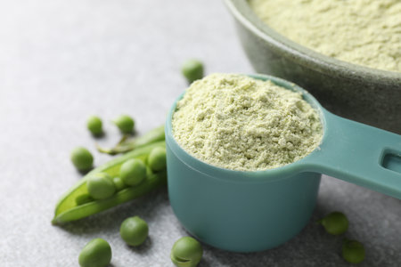 Protein powder and fresh green peas on light grey table, closeupの写真素材
