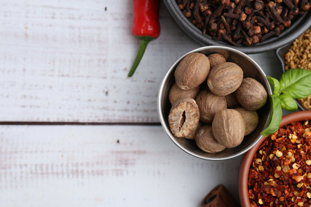Different aromatic spices on white wooden table, flat lay. Space for text