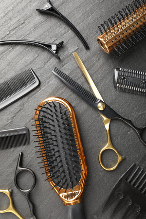 Different hairdresser's tools on dark table, flat lay