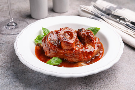 Traditional ossobuco dish with beef steak served on gray table, closeupの写真素材