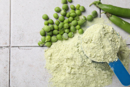 Protein powder and green peas on light tiled table, flat layの写真素材