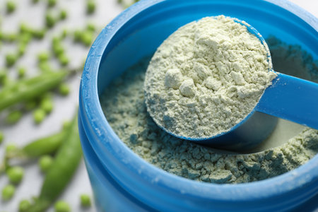 Protein powder and fresh green peas on light gray table, closeupの写真素材