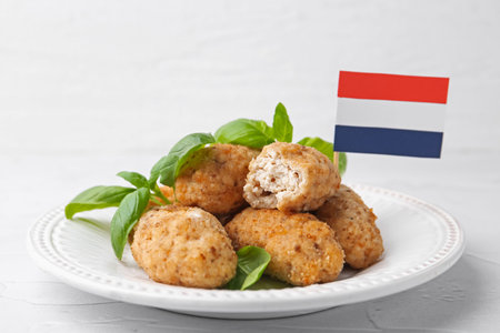 Tasty fried croquettes, basil and flag of Netherlands on white textured table, closeupの写真素材