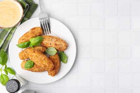 Tasty fried croquettes, basil and sauce on white tiled table, flat lay. Space for textの写真素材