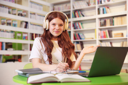 Student with laptop studying at table in library