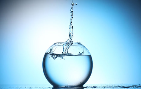 Glass aquarium with water on light blue background