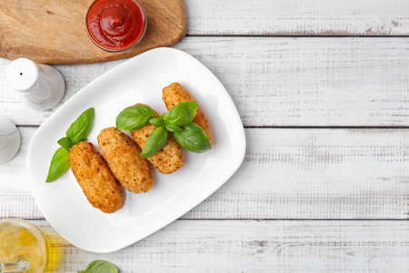 Tasty fried croquettes, basil and sauce on white wooden table, flat lay. Space for textの写真素材