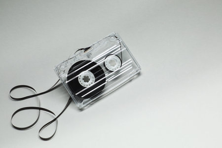 One audio cassette with magnetic tape on grey background, above view