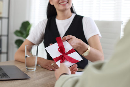 Boss giving gift to employee in office, closeup