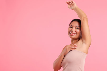 Woman showing hairless armpit after epilation procedure on pink background, space for textの写真素材
