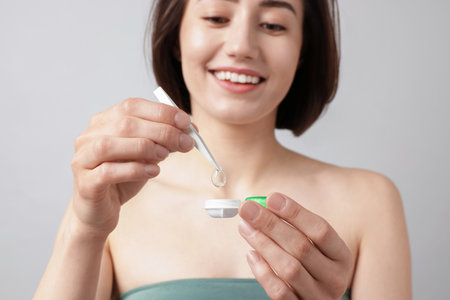 Woman taking contact lens out of case on light background, selective focusの写真素材