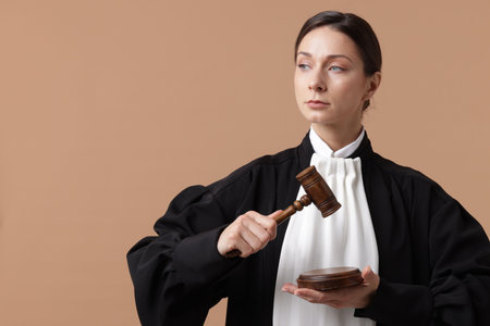 Judge with mallet and sound block on light brown background, space for text