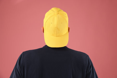 Young man in stylish baseball hat on pink background, back viewの写真素材