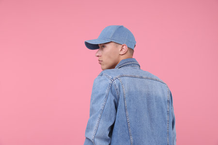 Young man wearing stylish denim baseball hat on pink background, space for textの写真素材