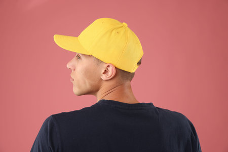 Young man in stylish baseball hat on pink backgroundの写真素材