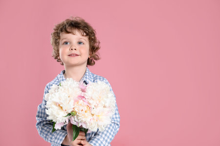 Cute little boy with bouquet of beautiful peonies on pink background. Space for textの写真素材