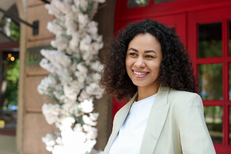 Portrait of smiling Latin American woman near building outdoors. Space for text