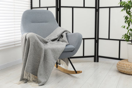 Comfortable armchair with gray woolen blanket indoorsの写真素材