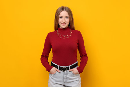 Portrait of smiling teenage girl on yellow background