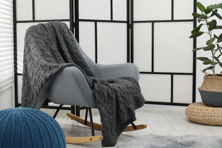 Comfortable armchair with gray woolen blanket indoorsの写真素材